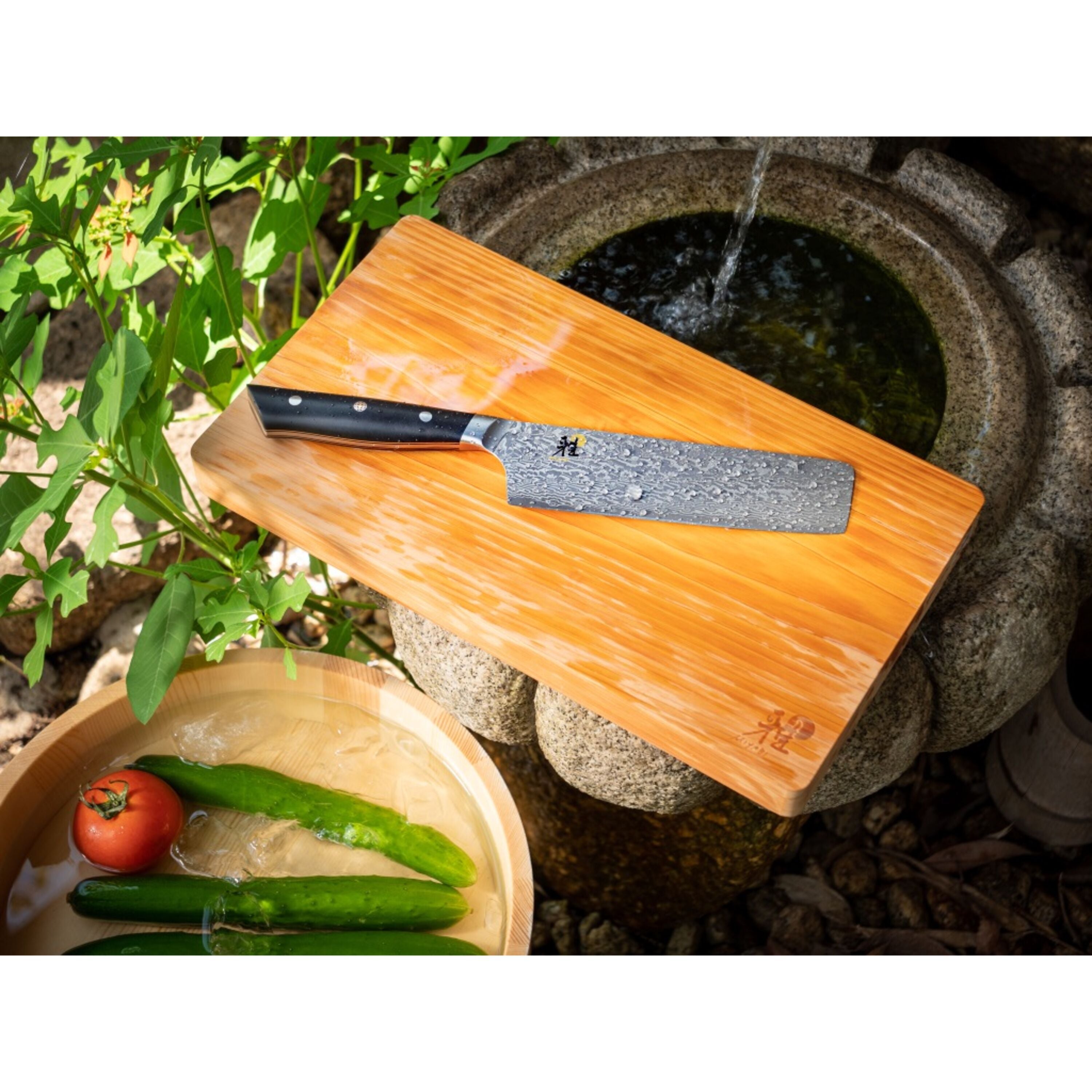 Miyabi Hibana 800DP 6.5” Nakiri Knife - Damascus Steel displayed on wooden cutting board with fresh vegetables nearby.