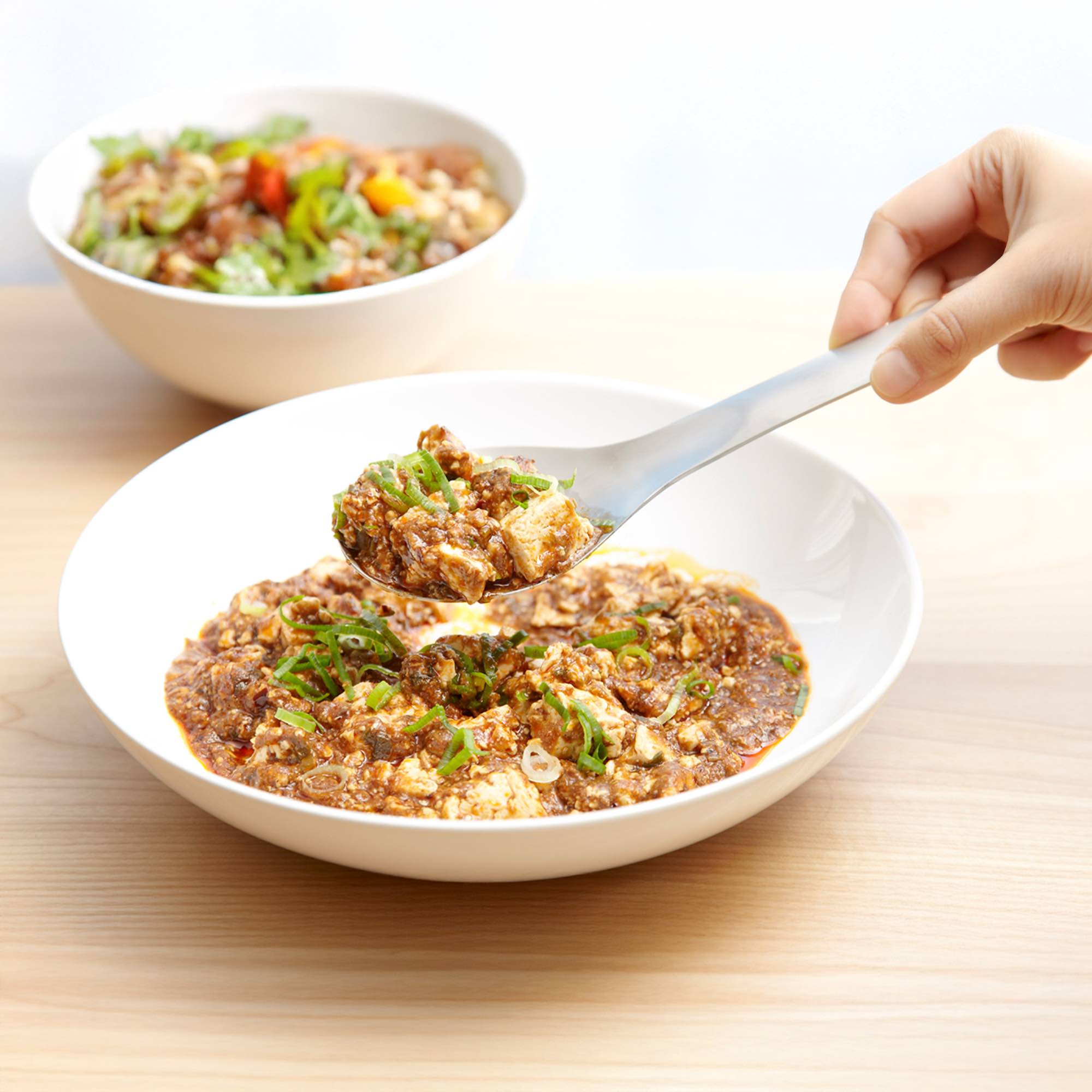 Eatoco Stainless Steel Serving Spoon elegantly serving a delicious dish from a bowl.