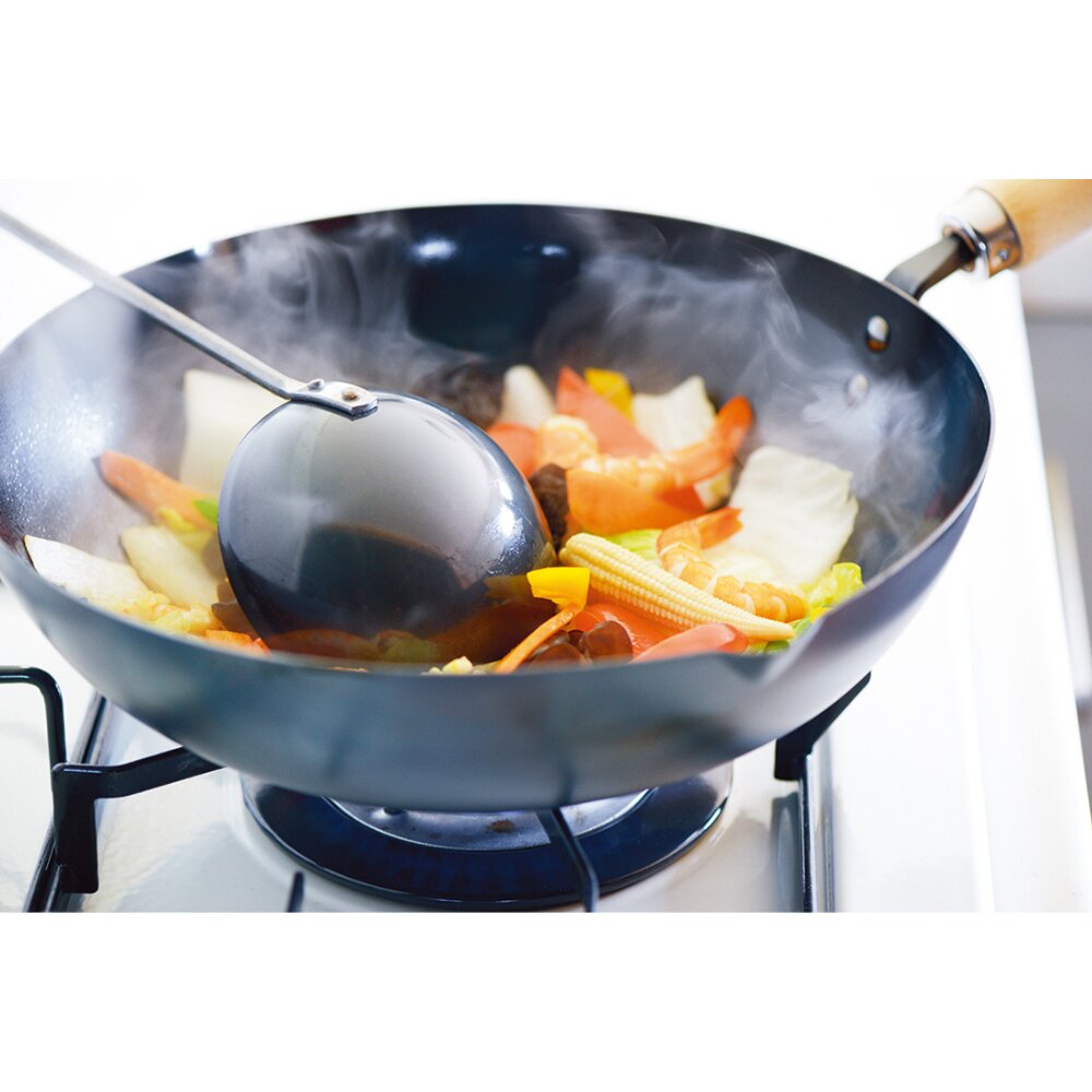 Wok with vegetables being cooked on a stove