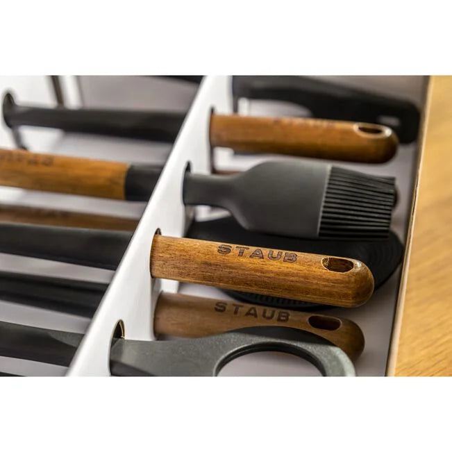 Staub Silicone Kitchen Utensil Set showing black silicone tools with acacia wood handles in a neat arrangement.