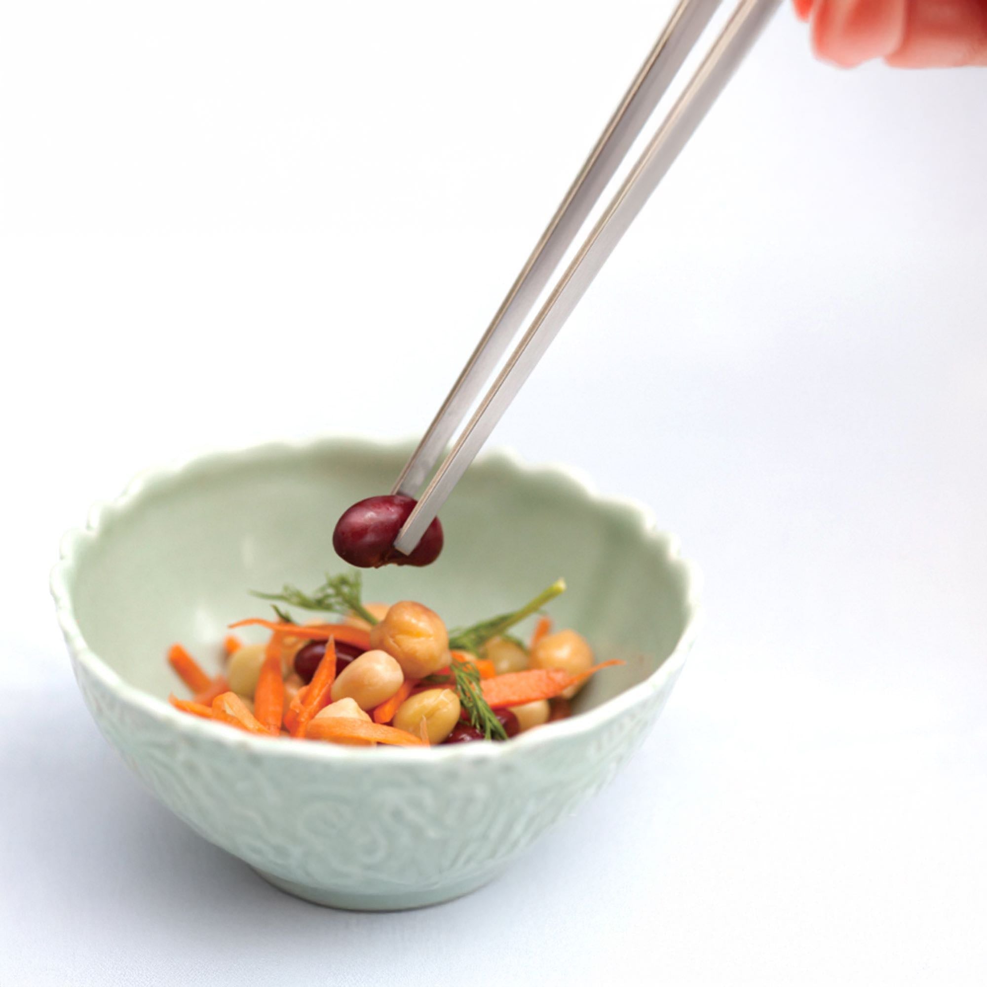 Eatoco Japan Stainless Steel Saibashi Tongs used to pick up colorful vegetables in a bowl.