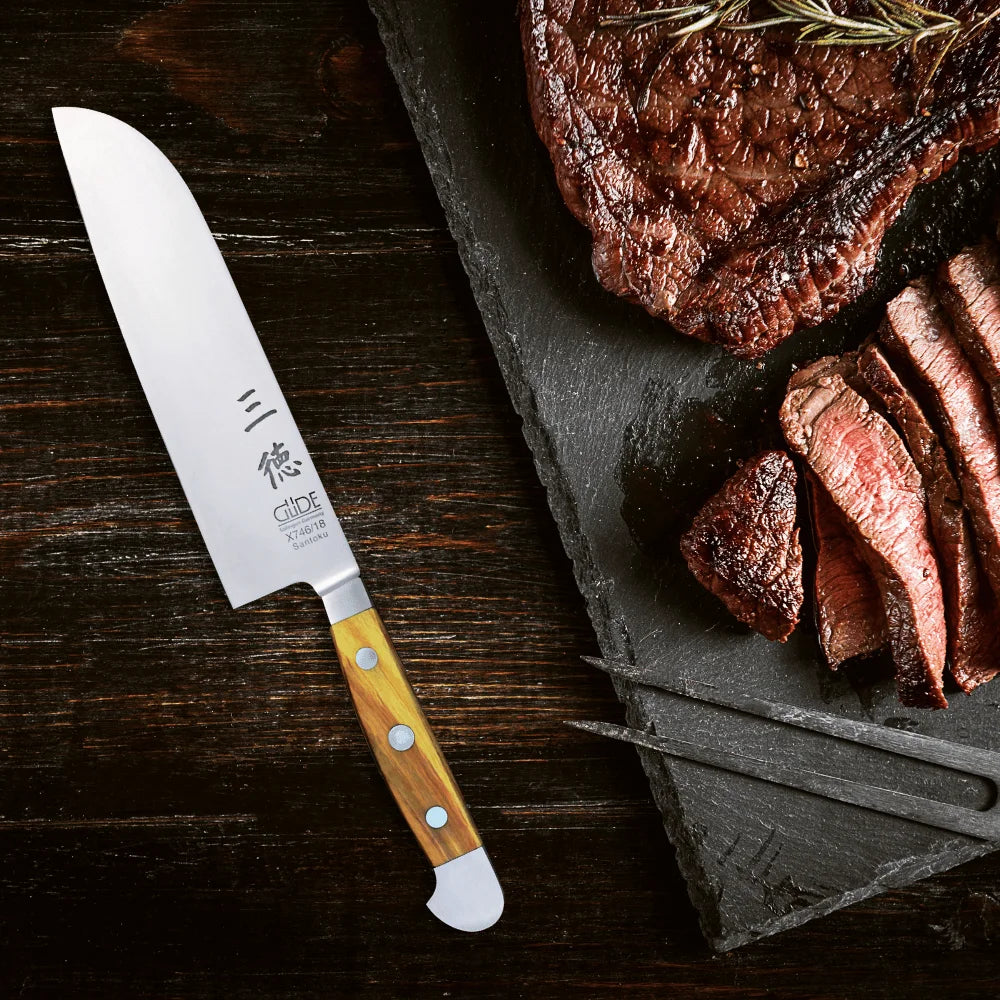 GÜDE Alpha Olive Chef Knife resting on a board