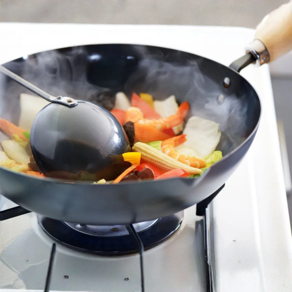 Yoshikawa Cook-Pal Ren Nitrided Carbon Steel Wok with vegetables being cooked on a stove